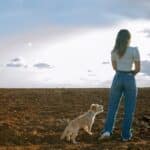 Young,Woman,Looking,At,The,Horizon,With,Her,Dog,,With